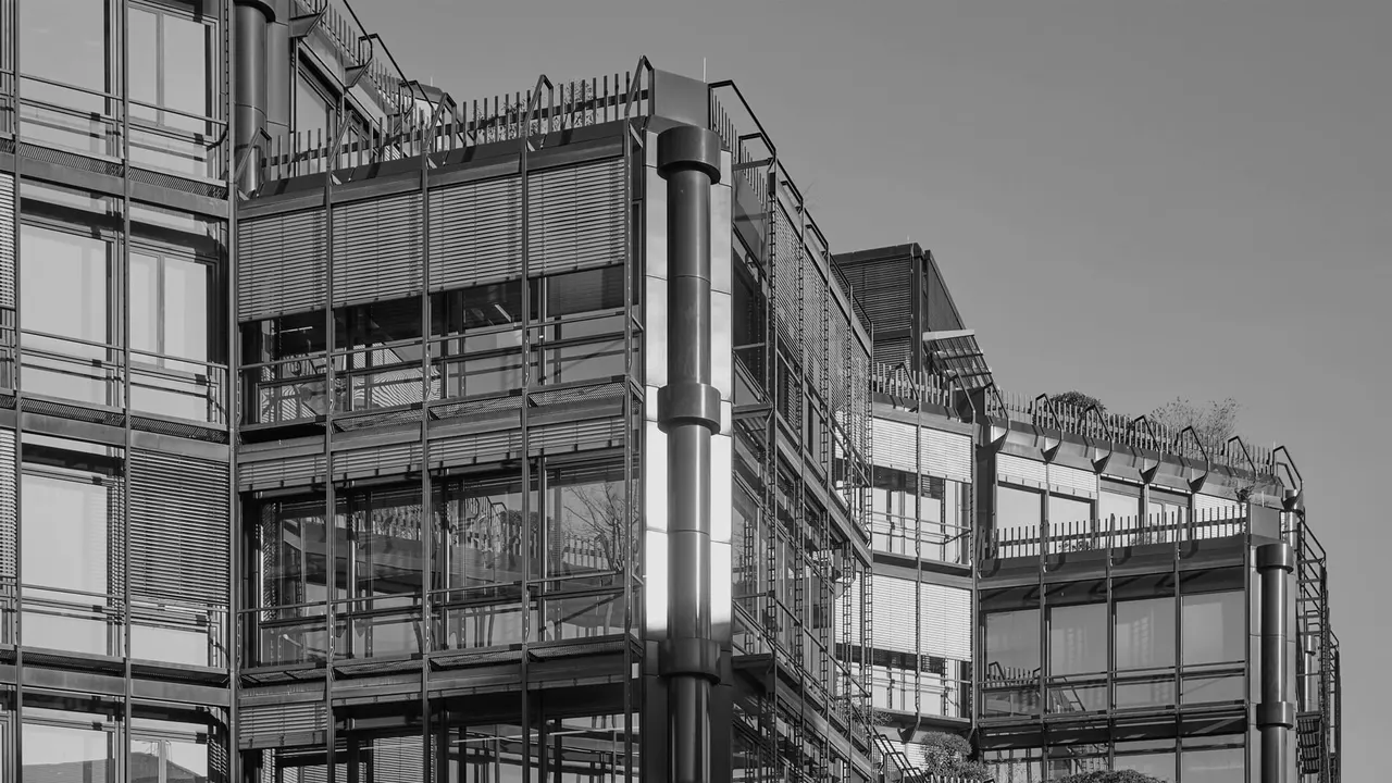 Fassade des Bürogebäudes mit Raffstoren, Laufstegen und begrünter Dachkante